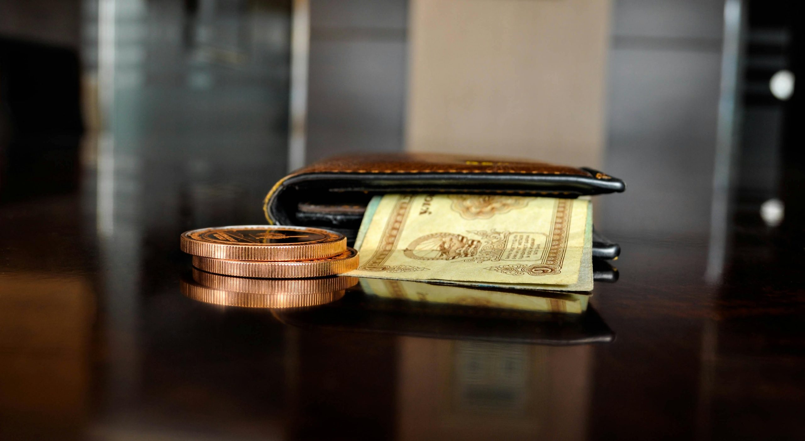 Wallet with cash and coins on a table, symbolizing financial vulnerability and risk of debt relief scams.